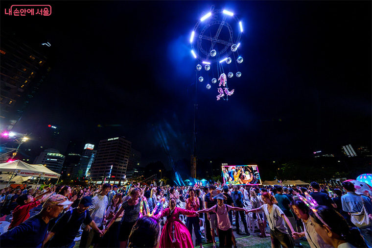 Seoul autumn festivals 2025 street performance with international artists performing at Cheonggyecheon Stream with autumn foliage and city lights